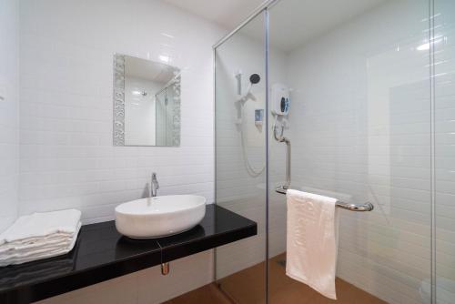 een witte badkamer met een wastafel en een douche bij Crystal Garden Hotel (Tasik Selatan) in Kuala Lumpur