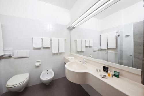 a bathroom with a toilet, sink, and mirror at Hotel Ai Gelsi in Codroipo