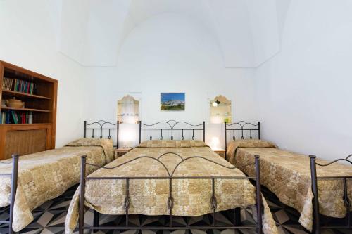 a bedroom with three beds and a book shelf at Casa vacanza La Stradella in Ostuni