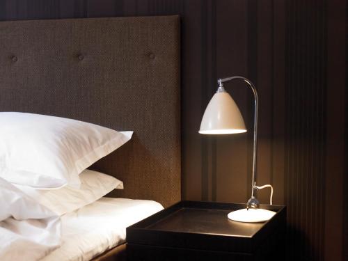 a lamp sitting on a night stand next to a bed at First Hotel Grand in Odense