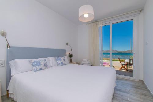 a white bedroom with a bed and a view of the ocean at Villa LA CALMA Alcudia in Alcudia