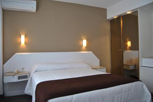 a bedroom with a large white bed and two lights at Hotel Castilla in Punta del Este