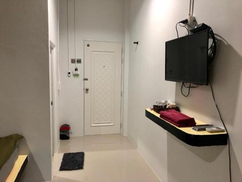 a hallway with a white door and a television on a wall at chillchillsangkhlaburi โรงแรมชิลชิลสังขละบุรี in Sangkhla Buri