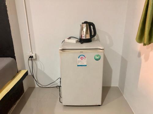 a small refrigerator with a kettle on top of it at chillchillsangkhlaburi โรงแรมชิลชิลสังขละบุรี in Sangkhla Buri