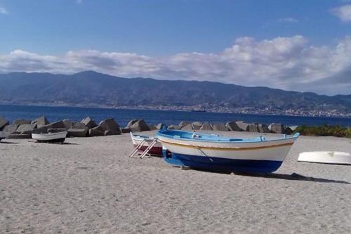 a blue and white boat on a sandy beach at L'Antica Locanda in Catona