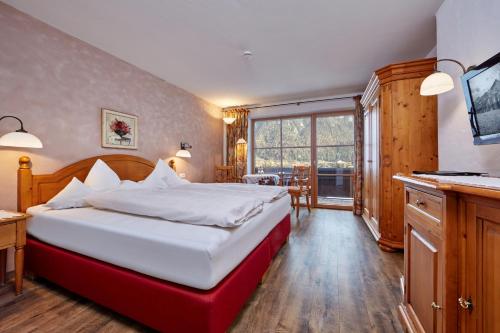 ein Schlafzimmer mit einem großen Bett und einem großen Fenster in der Unterkunft Landhaus Sonnenbichl Mittenwald in Mittenwald