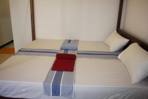 a bed with two pillows and a red towel on it at Baywings Rooms in Arugam Bay