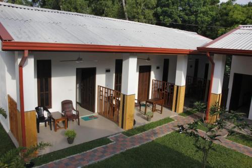 a small house with chairs and a porch at Baywings Rooms in Arugam Bay