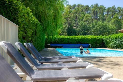 - un ensemble de chaises longues au bord de la piscine dans l'établissement VTF Les Florans, à Bédoin