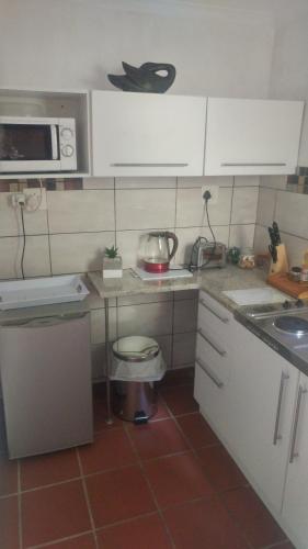een kleine keuken met een spoelbak en een magnetron bij Love Joy Peace Cottage in Pretoria
