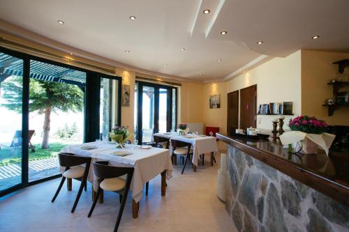 a restaurant with tables and chairs and large windows at Aetovigla Guesthouse in Krousón