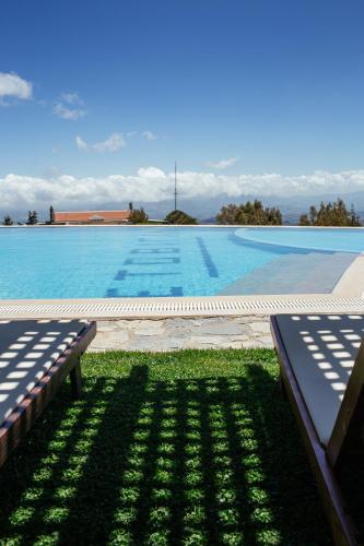 a large swimming pool with two benches in the grass at Aetovigla Guesthouse in Krousón
