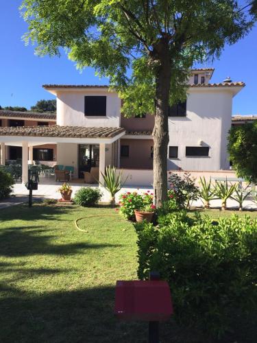a large white house with a tree in the yard at Verdemare Sardegna Uno in Villasimius
