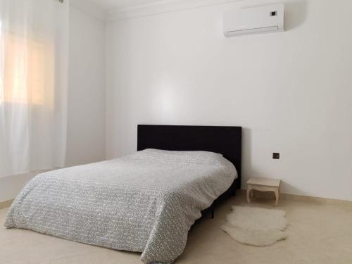 - une chambre blanche avec un lit et un tapis dans l'établissement Appartement cocooning à saidia proche toutes commodités, à Saïdia
