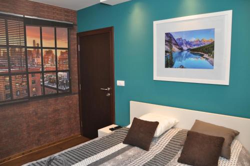 - une chambre avec un lit et un mur bleu dans l'établissement Lux apartman Čačak, à Čačak