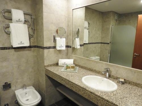 a bathroom with a sink and a mirror and a toilet at Konke Buenos Aires Hotel in Buenos Aires