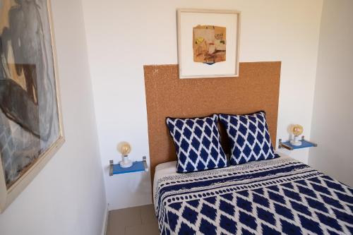 sypialnia z łóżkiem z niebiesko-białą kołdrą w obiekcie Absolument Levant w mieście Île du Levant