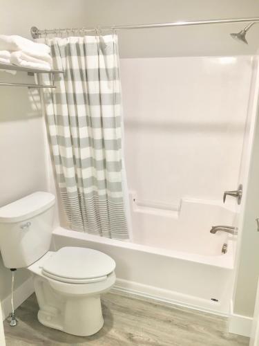 a white bathroom with a toilet and a bath tub at Empire Lakeshore Inn in Empire