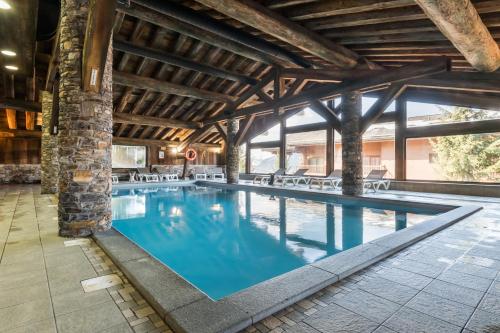 une grande piscine avec de l'eau bleue dans un immeuble dans l'établissement Résidence Pierre & Vacances Premium Les Alpages de Chantel, à Arc 1800