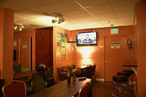 a room with a table and chairs and a tv on the wall at Adelaide Hostel in San Francisco