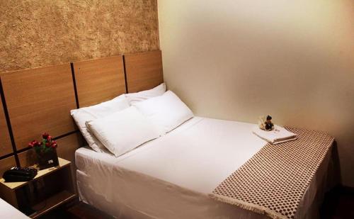 a bedroom with a white bed with a wooden headboard at Santa Maria Park Hotel in Garça