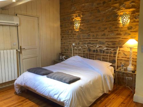 - une chambre avec un lit blanc et un mur en pierre dans l'établissement Appartement piscine, à Tonneins