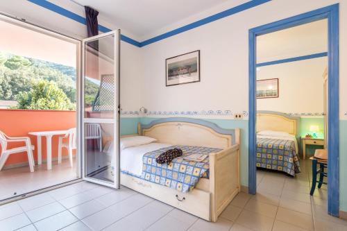 a bedroom with a bed and a balcony with a table at TH Ortano - Ortano Mare Residence in Rio Marina