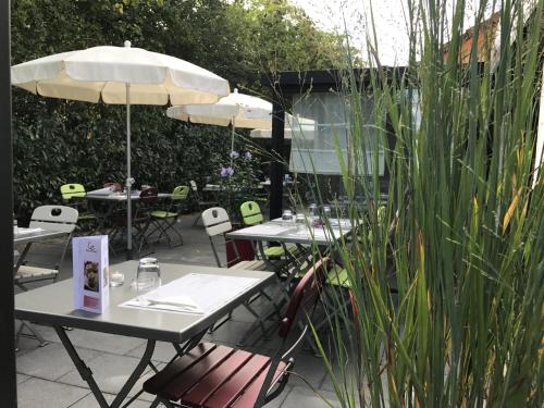 a patio with tables and chairs and an umbrella at Campanile Colmar - Parc des Expositions in Colmar