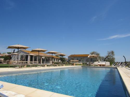 a large swimming pool with chairs and umbrellas at Agriturismo Sweet Cottage in Marina di Grosseto