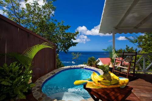 Ein Pool mit Bananen und Ananas auf dem Tisch. in der Unterkunft Ti Kaye Resort & Spa in Anse La Raye
