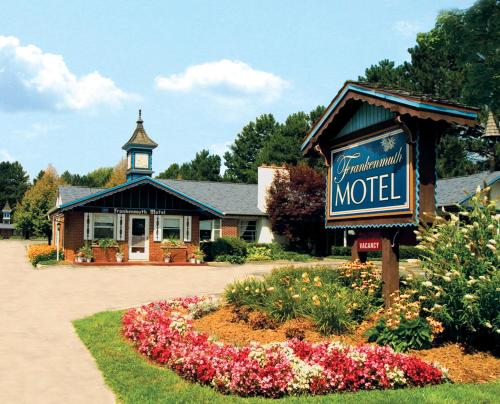 un motel avec un panneau et des fleurs devant lui dans l'établissement Frankenmuth Motel, à Frankenmuth