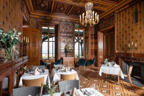 a restaurant with tables and chairs and a chandelier at Schloss Schadau - Swiss Historic Hotel in Thun