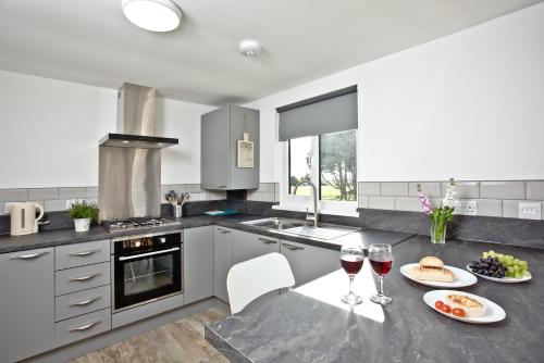 a kitchen with a table with two glasses of wine at Wheal Rose -Beautifully Fitted Lodge Helston Cornwall in Helston