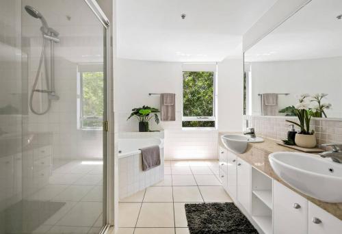 uma casa de banho branca com 2 lavatórios e um chuveiro em Waterfront Elegance Maroochydore em Maroochydore