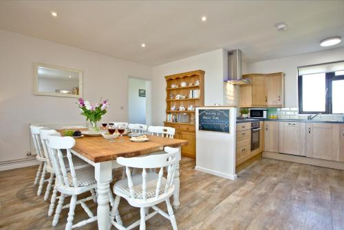 a kitchen with a wooden table and white appliances at Wheal Frances-Beautifully Fitted Bungalow Helston Cornwall in Helston