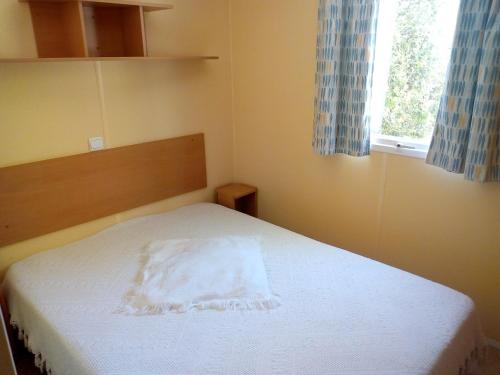 una piccola camera da letto con un letto bianco e una finestra di Camping Le Vialaret a Nant