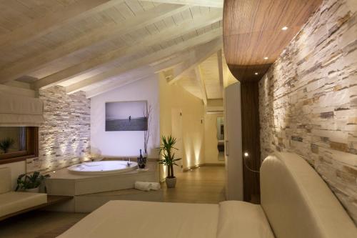 a bathroom with a tub and a stone wall at Hotel Barracuda in Marina di Campo