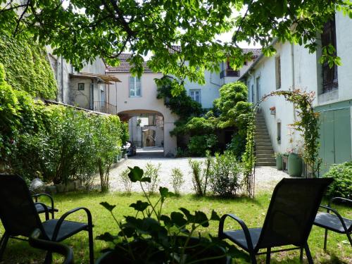 einen Garten mit Stühlen im Hof eines Hauses in der Unterkunft Les Glycines in Le Vigan