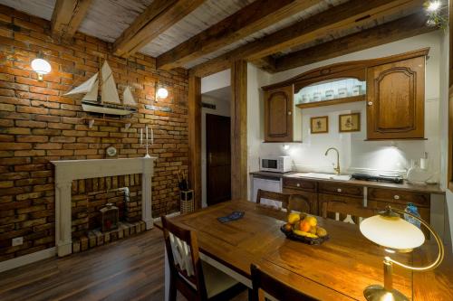une cuisine avec une table en bois et un mur en briques dans l'établissement Old House Apartments Poznań, à Poznań