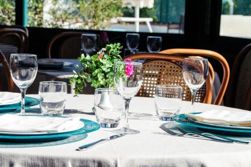 un tavolo con bicchieri, piatti e un fiore sopra di Hotel Gaby a Rimini