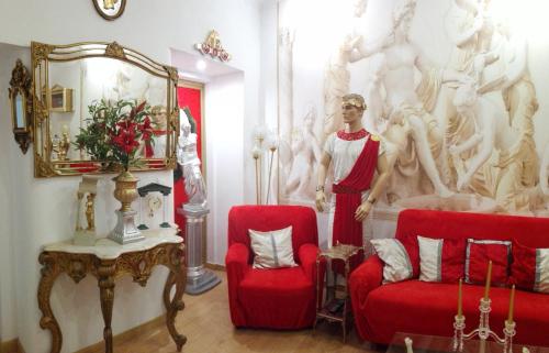 a room with two red chairs and a statue of a woman at Império Romano Guest House in Beja