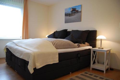 Cette chambre comprend un grand lit et une table de nuit. dans l'établissement Haus Abendsonne, à Sankt Peter-Ording