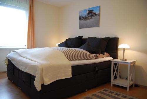 un grande letto in una stanza con comodino di Haus Abendsonne a Sankt Peter-Ording