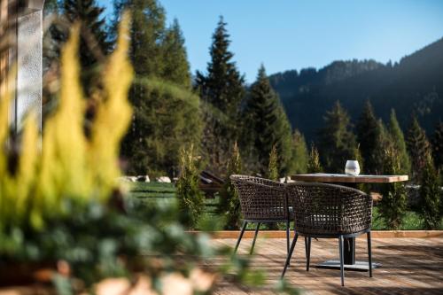two chairs and a table on a patio with a mountain at Les Dolomites Mountain Lodges in San Martino in Badia