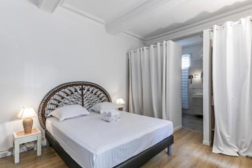 - une chambre avec un lit doté de draps blancs et de rideaux blancs dans l'établissement Villa jeu de paume - Première conciergerie, à Montpellier