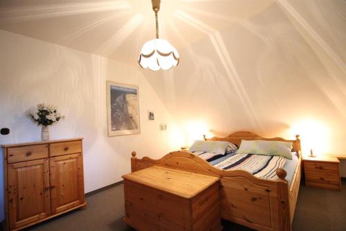 a bedroom with a wooden bed and a chandelier at Gästehaus Andresen-Warft in Tating