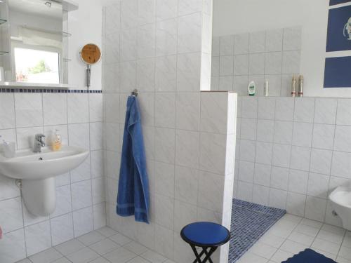 a white bathroom with a sink and a blue towel at Sonnenoase in Tating