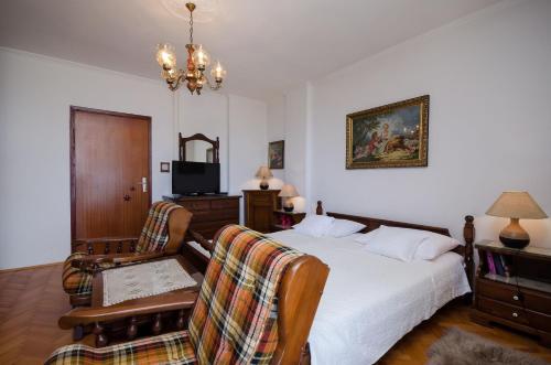 een slaapkamer met een bed en 2 stoelen en een televisie bij Apartments Zeljko in Lovran