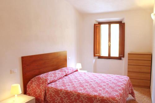 1 dormitorio con 1 cama con colcha roja y ventana en La Dimora nel Parco - ArgonautiVacanze, en Rio Marina