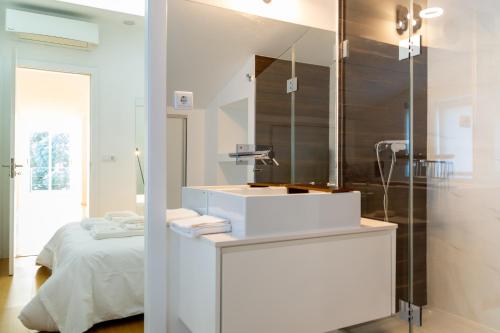 a white bathroom with a sink and a bed at H. S. Caloura in Lagoa